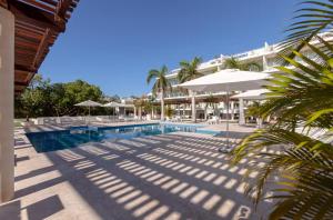 a swimming pool with umbrellas and a resort at Magia beachside condos in Playa del Carmen