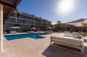 a hotel with a pool and chairs and a building at Magia beachside condos in Playa del Carmen