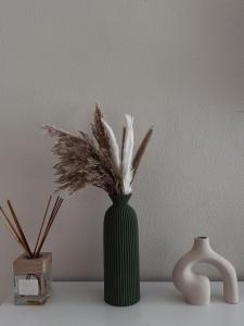 een groene vaas met veren op een tafel bij Dimora Bohém in Cantù