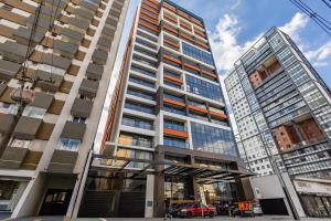 un grand immeuble avec une voiture rouge devant dans l'établissement Edificio MUV Yogha, à Curitiba 2 autres photos