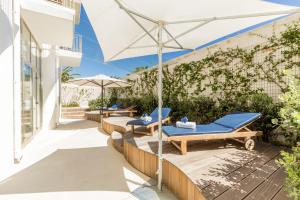a patio with two lounge chairs and an umbrella at The Pelican Beach Resort & SPA - Adults Only in Olbia