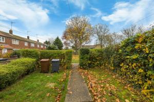 un jardin avec deux poubelles et une haie dans l'établissement Modern Comfort, Free Parking, Netflix & Disney plus in every Bedroom and Living Room, à Shephall