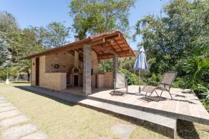 un patio con dos sillas y una sombrilla en Sitio Rodeado de Verde c Piscina e Churrasqueira, en Cinco Lagos