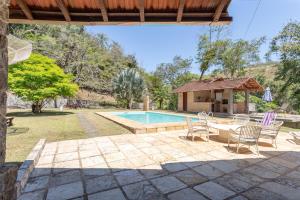Un patio con mesa y sillas junto a una piscina. en Sitio Rodeado de Verde c Piscina e Churrasqueira, en Cinco Lagos