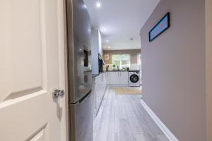 une porte ouverte sur une cuisine avec des armoires blanches dans l'établissement Modern Comfort, Free Parking, Netflix & Disney plus in every Bedroom and Living Room, à Shephall