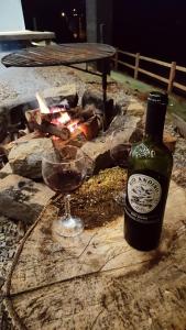 Eine Flasche Wein und zwei Weingläser stehen neben einem Feuer. in der Unterkunft Charmoso Chalé container em Piracaia, in Piracaia + 20 Fotos