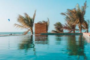 a swimming pool next to a beach with palm trees at Villa Caraúbas in Camocim