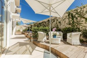 a patio with a table and chairs and an umbrella at The Pelican Beach Resort & SPA - Adults Only in Olbia