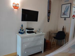 a bedroom with a dresser with a tv on the wall at Studio Le Balisier in Caritan
