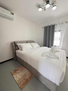 ein Schlafzimmer mit einem Bett mit weißen Laken und einem Fenster in der Unterkunft Wasana Village Phutoei in Ban Phu Toei