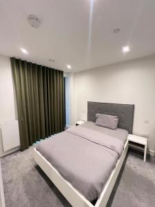 a bedroom with a large bed and a green curtain at 2 Bedroom Brentford in Kew Bridge +8 photos