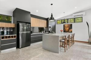 Balinese Style Villa With Bionized Pool في Bayview Heights: مطبخ مع طاولة مع كراسي وثلاجة