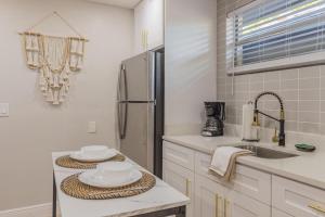 a white kitchen with a refrigerator and a sink at CUTE and COZY studio w jacuzzi in Orlando