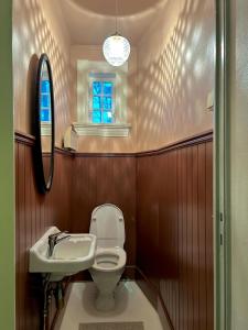 a bathroom with a toilet and a sink and a mirror at Historic villa with large garden in Stord