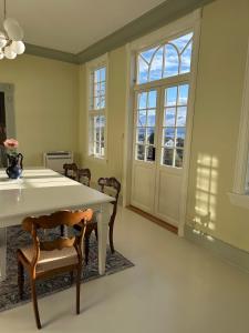 a dining room with a table and chairs and windows at Historic villa with large garden in Stord +28 photos