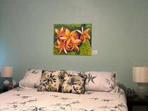 ein Blumengemälde an der Wand über einem Bett in der Unterkunft Hawaiian Coffee Hale in Redding + 2 Fotos