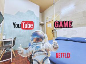 Ein Mann im Astronautenanzug, der die Daumen nach oben drückt. in der Unterkunft Hive28 in Bang Kapi