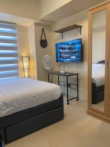 Un dormitorio con una cama y un televisor en la pared. en Cozy Studio Unit Near IT Park with Pool Access, en Mabolo