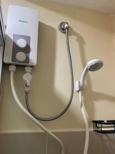 una manguera conectada a un cabezal de ducha en una pared en Cozy Studio Unit Near IT Park with Pool Access, en Mabolo
