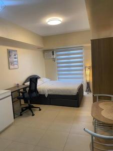 Un dormitorio con una cama, un escritorio y una silla. en Cozy Studio Unit Near IT Park with Pool Access, en Mabolo 12 fotos más