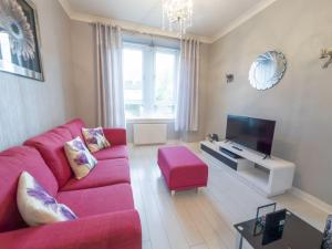un salon avec un canapé rouge et une télévision dans l'établissement Central Renfrew 1BR Apt, à Renfrew