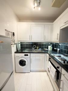 une cuisine blanche avec une machine à laver à l'intérieur dans l'établissement Central Renfrew 1BR Apt, à Renfrew