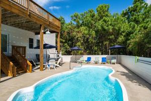 Una piscina con sillas y sombrillas al lado de una casa. en Tee Dreams - C0432, en Sanderling
