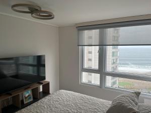 ein Schlafzimmer mit einem Bett und einem großen Fenster in der Unterkunft Departamento completo in Iquique