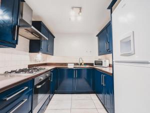 a kitchen with blue cabinets and a white refrigerator at Modern 2-Bed Near Braehead in Renfrew