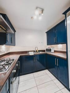 a kitchen with blue cabinets and a stove top oven at Modern 2-Bed Near Braehead in Renfrew