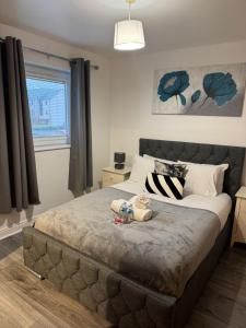 une chambre avec un lit avec deux animaux en peluche dessus dans l'établissement Modern 2-Bed Near Braehead, à Renfrew