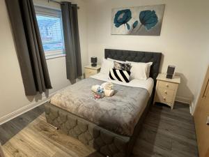 une chambre avec un lit avec un ours en peluche dessus dans l'établissement Modern 2-Bed Near Braehead, à Renfrew
