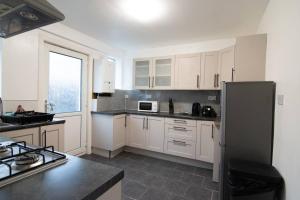 une cuisine avec des armoires blanches et un réfrigérateur dans l'établissement Stylish 2BR in Renfrew, à Renfrew