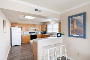a kitchen with white appliances and wooden cabinets at SURFRIDER Dewey Beach Ocean Block in Dewey Beach