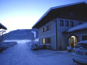a house in the snow with a car parked next to it at Abis Ferienwohnung Salzkammergut in Strobl