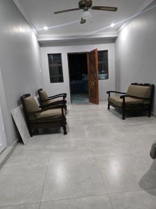 Apartment 33 في خليج ريتشاردز: غرفة معيشة مع كرسيين ومروحة سقف