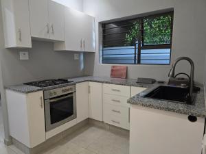 Apartment 33 في خليج ريتشاردز: مطبخ بخزائن بيضاء ومغسلة ونافذة