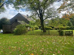 a yard with a fence and a house with a tree at Le Nid d'à côté in Méan