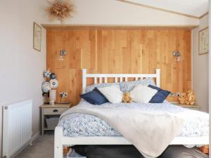 a bedroom with a white bed and wooden walls at Fairways 4 in Liskeard