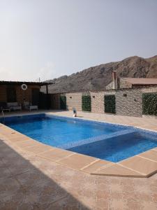 a swimming pool in front of a building with a mountain at Mountain Park Rest in Ḑab‘ah