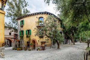 un grand bâtiment jaune avec volets verts dans l'établissement Cipressi Lofts Val'Quirico, à Santeagueda
