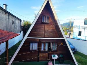 a small house with a pointed roof on a yard at Chalé da Vandisa in Ilhabela