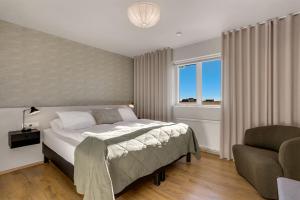 ein Schlafzimmer mit einem Bett, einem Stuhl und einem Fenster in der Unterkunft Kviholmi Premium Apartments in Hvolsvöllur