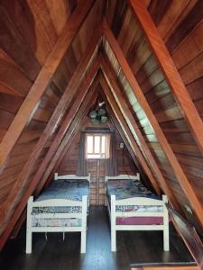 two beds in the attic of a log cabin at Chalé da Vandisa in Ilhabela