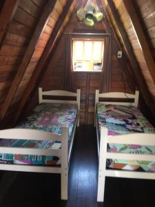 two beds in the attic of a log cabin at Chalé da Vandisa in Ilhabela