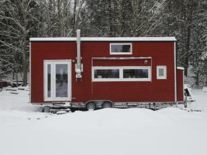 a red tiny house sitting in the snow at Stuga med bastu i naturen nära Stockholm in Järna