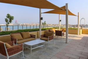 a patio with a couch and chairs and an umbrella at Beachfront Home with Sea View - 2BR, 134m2 in Lusail