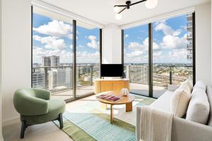 a living room with a couch and a tv and large windows at The Crosby Miami Worldcenter in Miami