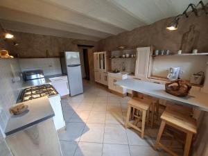 a large kitchen with a stove and a refrigerator at Gîte de Fond Carle in Miribel-Lanchâtre
