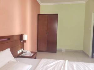 une chambre avec un lit et une armoire en bois dans l'établissement Hampton - Resorts, à Hohoe